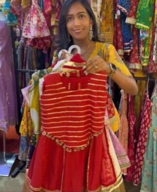 Holding up a red gota-stripe lehenga